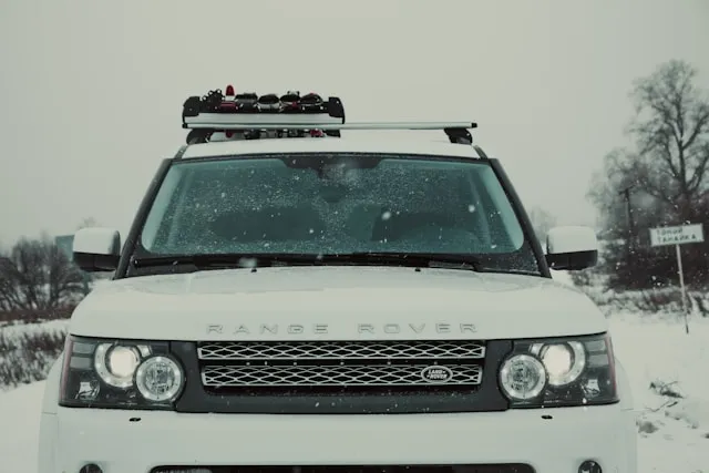 bagażnik na narty na białym Range Roverze w śnieżnym krajobrazie,